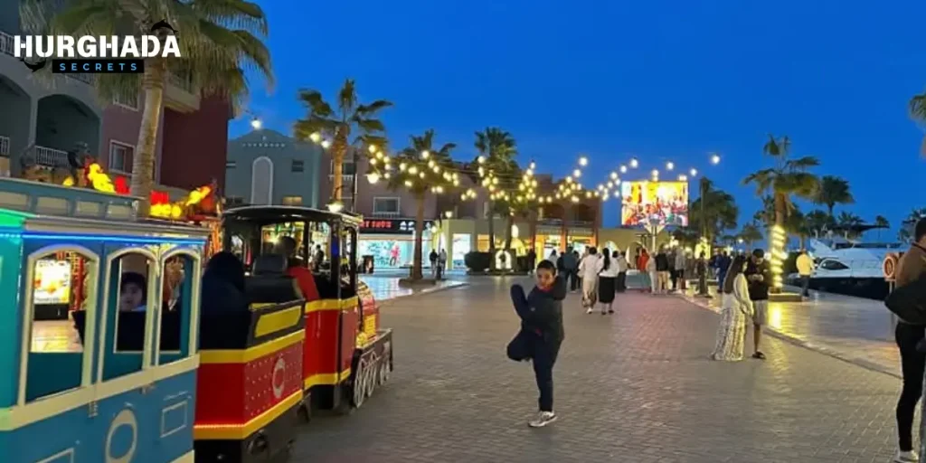 a-tour-in-hurghada-8 Tourists walking beside a red train in a palm-lined walkway in Hurghada