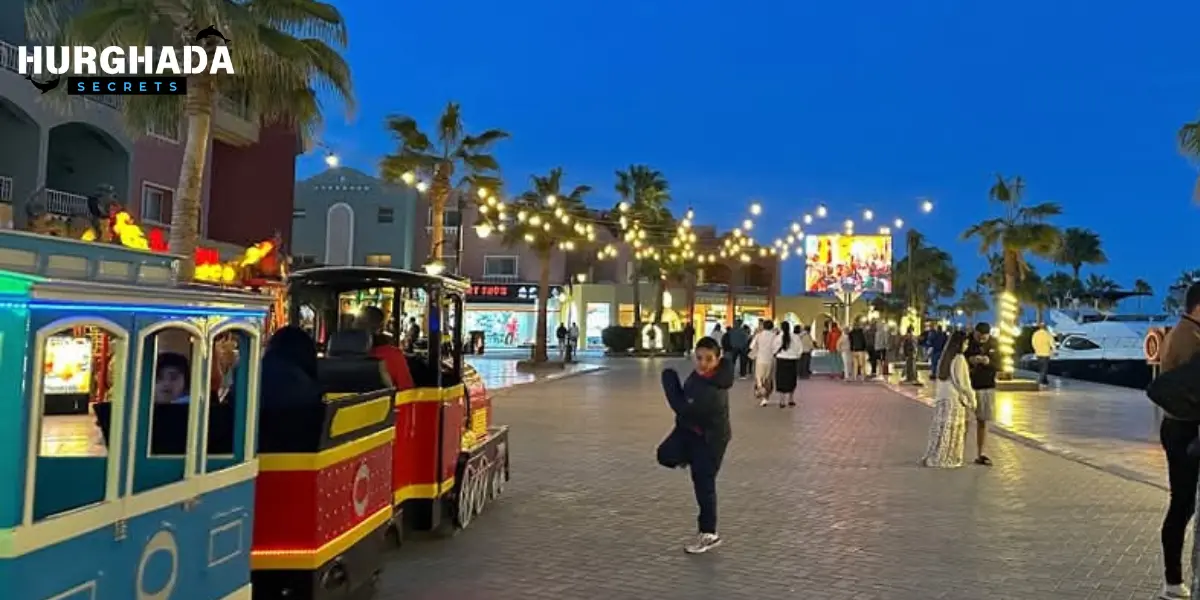 Tourists walking beside a red train in a palm-lined walkway in Hurghada
